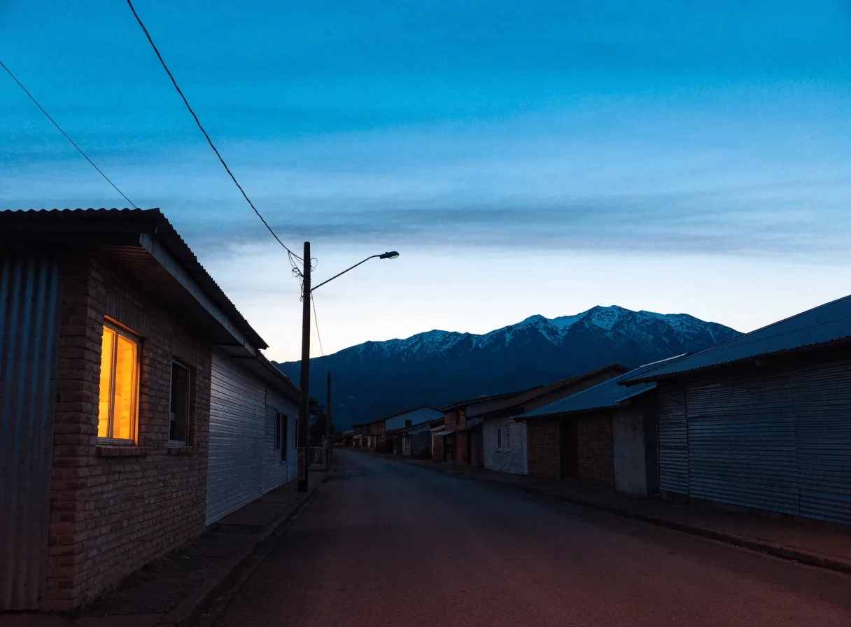 Calle de una localidad neuquina al atardecer, con montañas al fondo