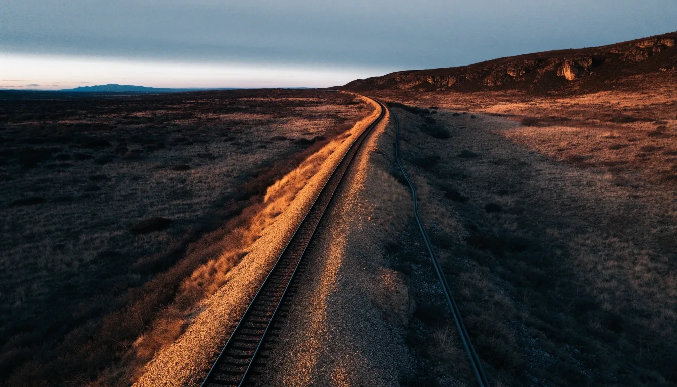 Traza ferroviaria y ducto paralelo cruzando la estepa patagónica al caer la tarde