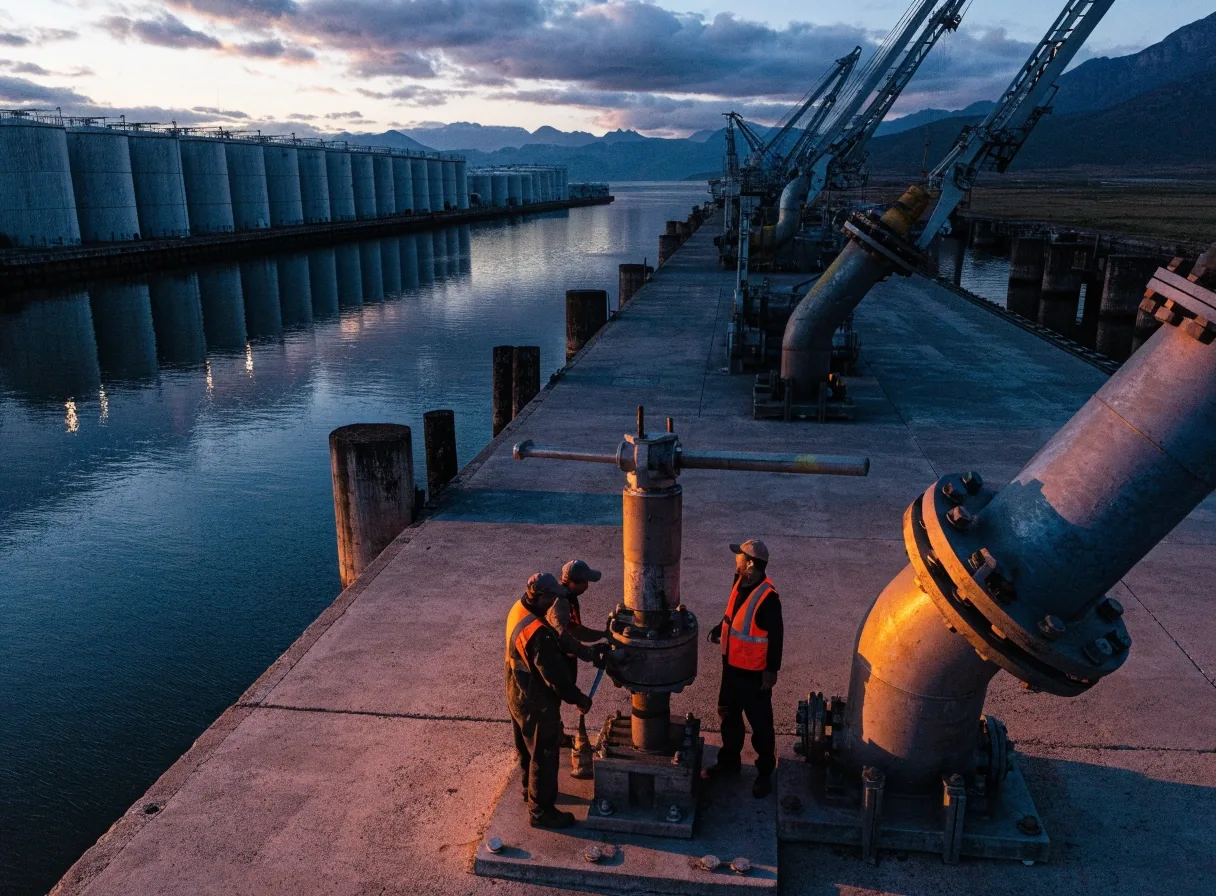 Terminal portuaria de exportación al atardecer con tanques de almacenamiento y brazos de carga